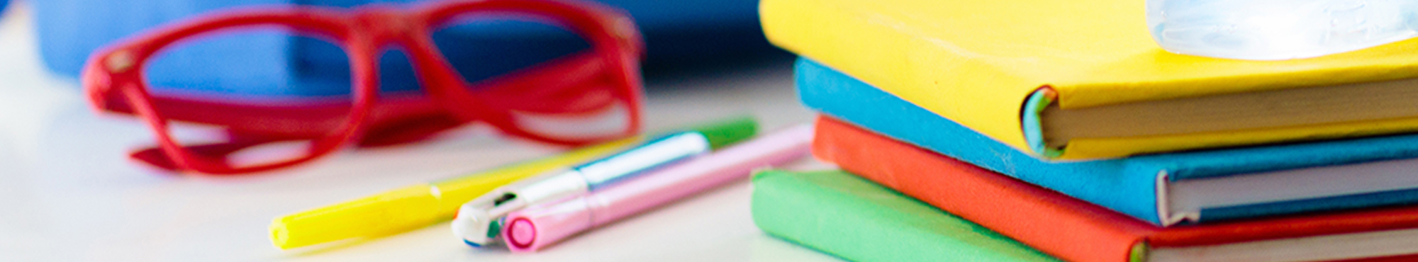 Child's backpack on table with books, glasses, and face mask