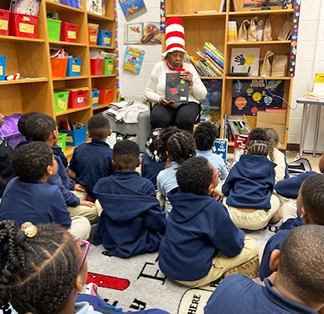 Adult wearing Dr. Seuss hat reading story to students